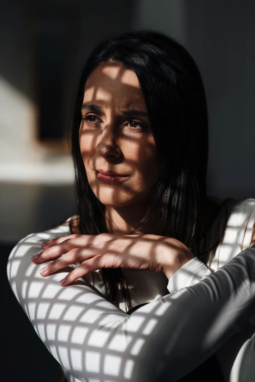Réka elgondolkodva ül, arcán és karján az ablakrács árnyéka