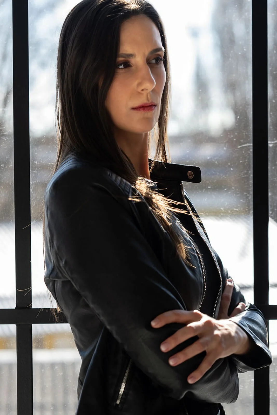 Réka bőrdzsekiben, karba tett kézzel, oldalra néz