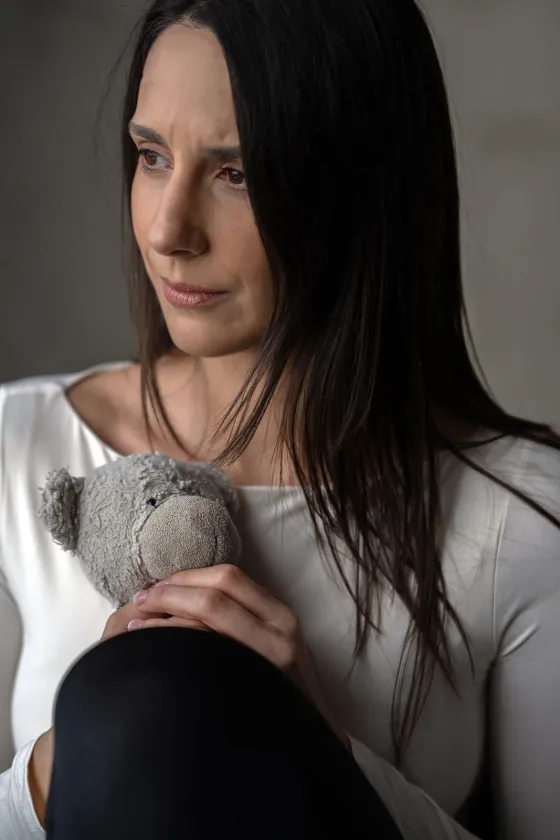 Réka egy plüssmacit ölel, szomorkás tekintettel